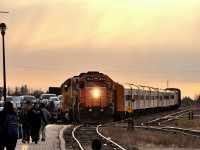 Playing in the sand at the Cochrane station, left from years of engines struggling to grip slick, slippery and icy rails during departure from the Cochrane station. Exploring the world he's in and enjoying the small beach created between the platform and rails a rumble approaches to the east. He looks up. A roar from Ontario Northland GP38-2's 1806 and 1809 as the Engineer increases the throttle to pull 4 flatbeads loaded with vehicles out of the ramp track and onto the main. The bell starts ringing to warn the awaiting passengers on the platform of the train's approaching presence. Startled, the boy in the picture runs to his parents side. In minutes the train will pull up to the station and into position to start loading the almost 300 people standing around to board for Moosonee. Thanksgiving Monday is a busy day for the northbound Polar Bear Express.