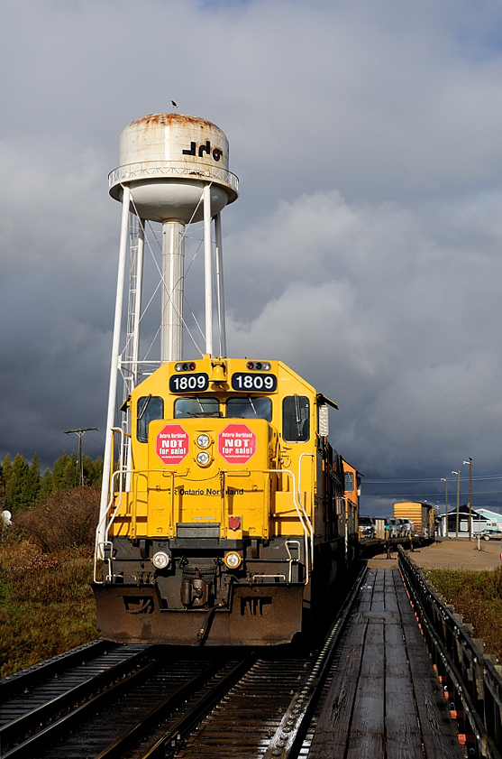 Storm clouds on the Horizon. There are dark times instore for Ontario's regional rail line. Cuts and layoffs have already taken effect with the previous weeks cancellation of the Northlander service between Cochrane and Toronto. One bright spot still is the requirement for Monday thru Friday "passenger mixed" service between Cochrane and Moosonee. The rain had stopped and the sun came out just as I got in position to take this classic shot of the Polar Bear Expressed nosed out onto the bridge with the water tower in the background.