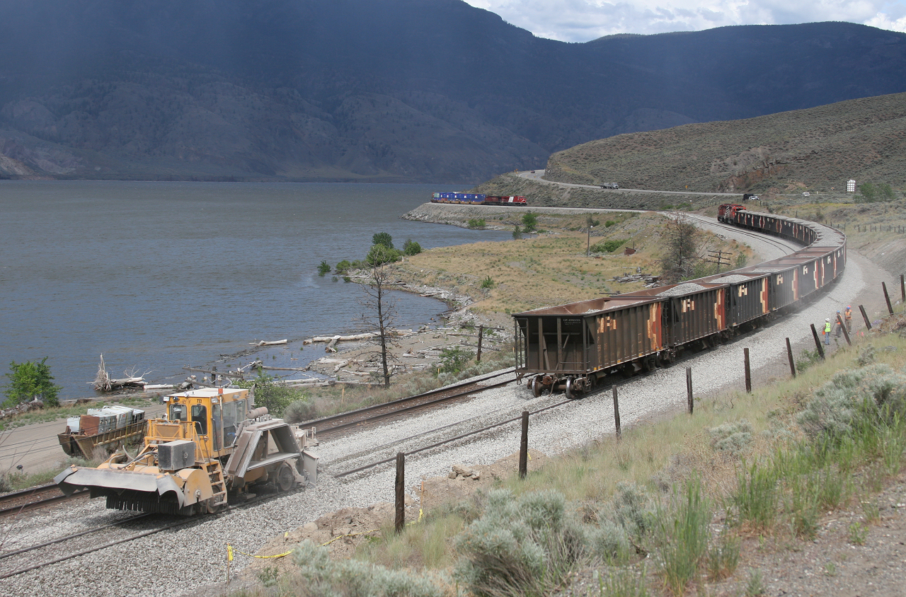 Rain falls over Kamloops Lake as Work 5952 dumps ballast on the siding extension at Savona with CP 8866 west approaching with a hotshot bound for the coast