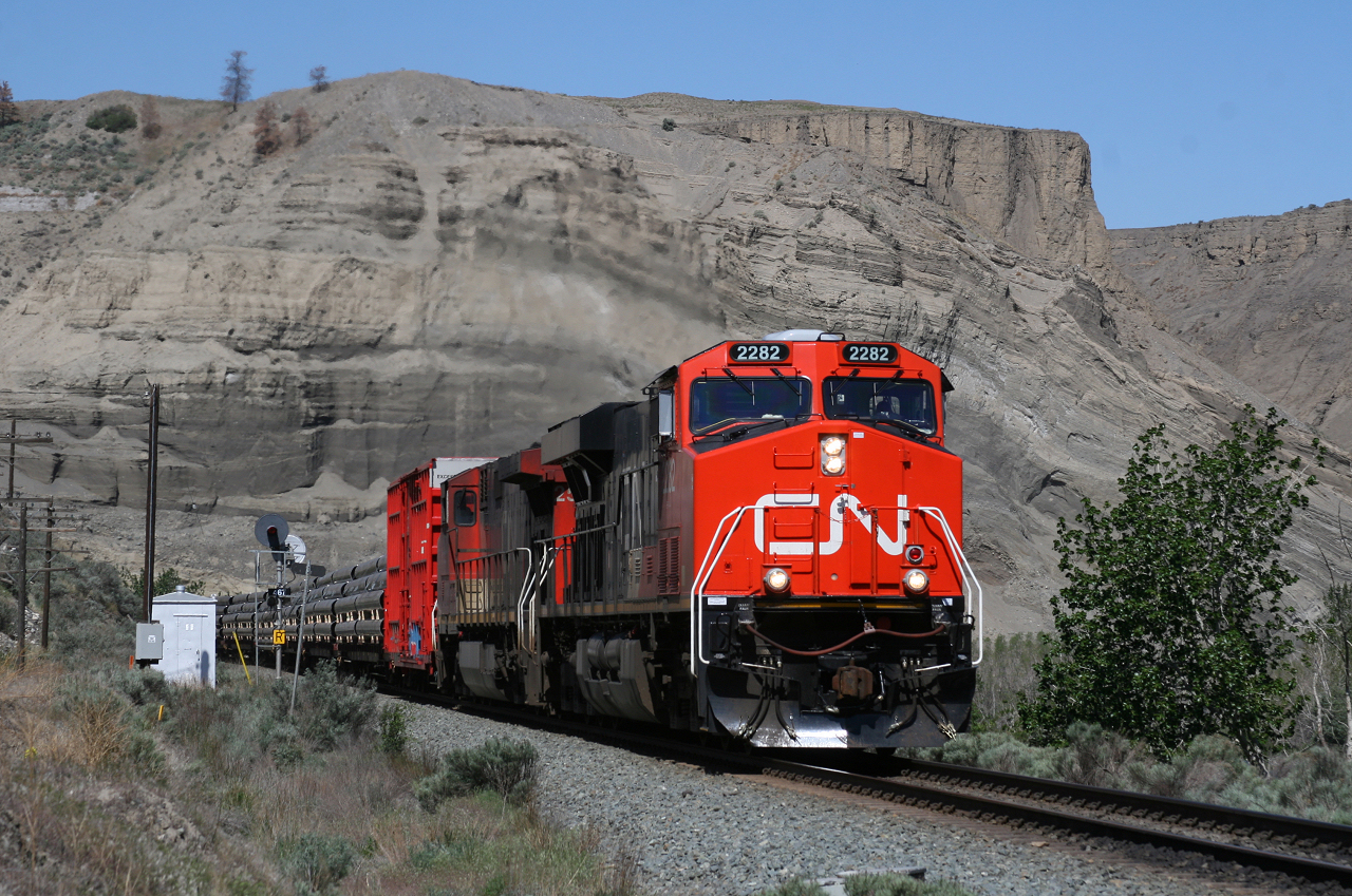 CN 302 highballs out of Ashcroft under the towering sandstone cliffs that briefly forces the CN over to the CP side of the Thompson River