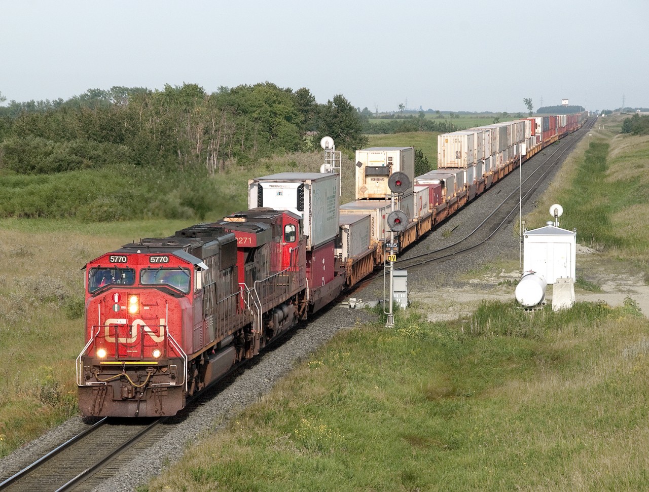 Eastbound intermodal 106 with lead SD75I 5770 passes the east switch at Moffat on the Rivers Sub just east of Justice elevator, in background.