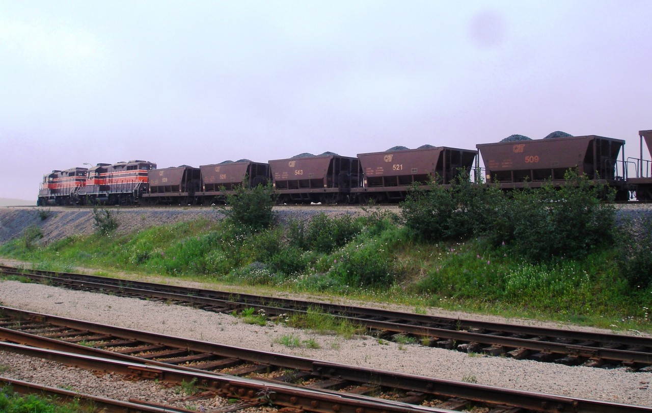 Riviere Romaine Railways QIT #39 and QIT #38 lead a string of precisely loaded ore cars onto the high line unloading bridge at the port in Havre St-Pierre. Both units are running short hood forward on this warm and hazy second last day of July.