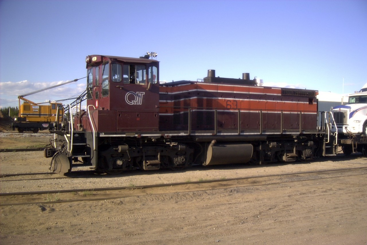 QIT 69 gets ready to leave for the mine with a tractor trailer loaded on a flat car.  Behind the locomotive sits QIT's recently purchased American 850-80 locomotive crane.