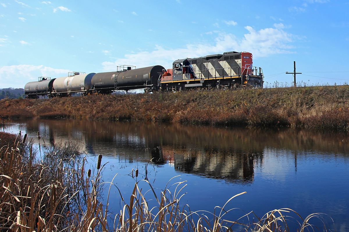 Taking advantage of the nice 75 degree sunny weather a member of the crew sits outside the cab as 4132 hauls 595 back to Huntsville, reflecting in the pond beside the tracks just south of Martins.