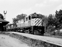 The Uhtoff Stone Train, with 4230-8795-5005 (C424-RS18-GP35), rolls through Alliston, Ontario on a warm 1978 summer afternoon.  Note the passenger waiting to flag train #12. Kodak Plus X negative by S.Danko.