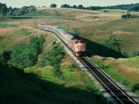 August 26, 1978 at the approach to Humber on the Mactier Subdivision in the Oak Ridges Moraine, an enormous CP Rail train #12, the Toronto section of The Canadian –  normally an eight car train – is a thirteen car train today! And only about one hour off the advertised. You are looking at the impact of an air traffic labour disruption (either a work to rule, lock out or strike – perhaps a viewer can clarify - for a week (or so) no regular passenger air travel). Both CP and CN had demand and ridership levels not experienced since the Centennial Year - 1967. What's interesting: It is rumoured that to re-position (ie send home) some CP Air crews the CP owned airline bought CP Rail tickets. CP Rail placed every available piece of passenger equipment, including the Angus Shop built 2200 series coaches, into service and on this train the Chateau sleeper in front of the Skyline Dome is in coach service. Look closely, the Vancouver originated equipment is coated in a fine layer of dust (see trailing image) while the Sudbury – Toronto only cars (the Skyline Dome, the Chateau sleeper in front of the Skyline and the Park car) are clean. It also appears that one of the 2200 series coach may have originated west of Sudbury. Certainly the FP7A #1432 (ex CP 4041) and the 1900 series F7B are getting a good workout. And at this location for the trailing image, an eight car train plus the power is easily in the whole frame, but today – surprise! And on the tail end the Park car is missing the drum head, likely sent to Montreal for sale by CP Archives - by October 1978 the train will be 'Via-ized'. Kodachrome by S.Danko.