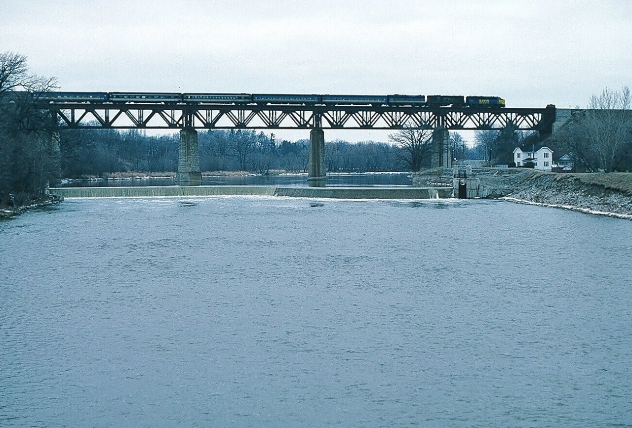 A  FPA-4 / RS-18 / F9B  lashup  (67xx, 31xx, 66xx)  powers Via Rail train #74 on the Grand River bridge at Paris. January 1980 Kodachrome by S.Danko.