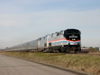 An Extra 694 with a train set leased from VIA Rail for 2 weeks on way to Albany , NY in L'Acadie borough of St-Jean sur Richelieu .