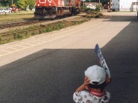 CN 5705 leads a freight through Brantford Ontario on a sunny July day.  A young railfan covers his ears from the squeeling of the wheels on the many freight cars that are on the freight.  That young railfan is now RP.ca contributor Joseph Bishop...where it all started trackside.