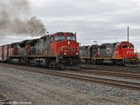 Accelerating after a quick crew change, CN 308 behind CN 2681, 8860 and DPU IC 1012 pass GTW 5937 IC 1021 drilling Herzog and CN ballast hoppers at the east end of the yard. 1200hrs.