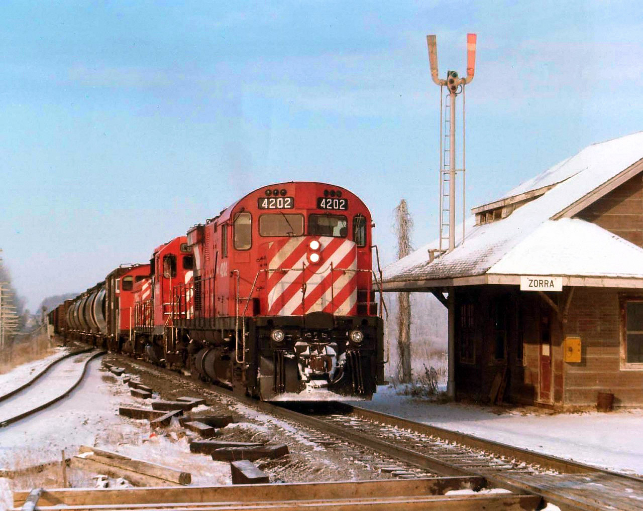On a day not quite spring, eastbound train #52, with CP 4202, 5022 and 6700 rolls past the old Zorra station. The track on the left veers off to the current La farge cement plant, and off to the right (out of sight) the line to St. Marys existed; now only a spur to a gravel operation.