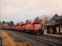 
Northbound CP 5637,5587,3094,30xx,5680,5402,CRL(Conrail Leasing)600 and CP 5933 roar off the big Parry Sound trestle past the dilapidated old CP station, abandoned in early 1990; and was a potential firetrap until resurrected by an outfit that opened the Parry Sound Station Gallery in 2001. In this image the gloomy old station matched the weather of the late fall day,  cold and wet.
It was indeed a relief for the fans that the station survived all those years neglected without going up in flames as a result of vandals or vagrants. (Note wood pried off one lower bay window in photo)"The Sound" is one of the few communities in Ontario that can boast still having two railroad stations. The CN sta. is less than a mile away, serves as C of C and License Bureau.