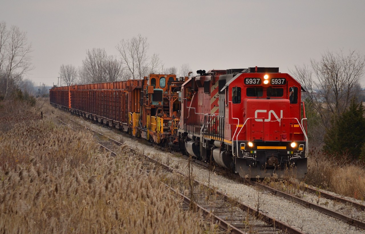 A cool gloomy morning sets the mood here. After just coming off of the Sarnia Spur and onto the CN CASO Sub, GTW 5937 & CP 6030 slowly pull the rail train to the first crossing west of Fargo where a CN foreman will watch it pass thru. The train will make its way to Essex today and start pulling track tomorrow as it heads back east towards Fargo.