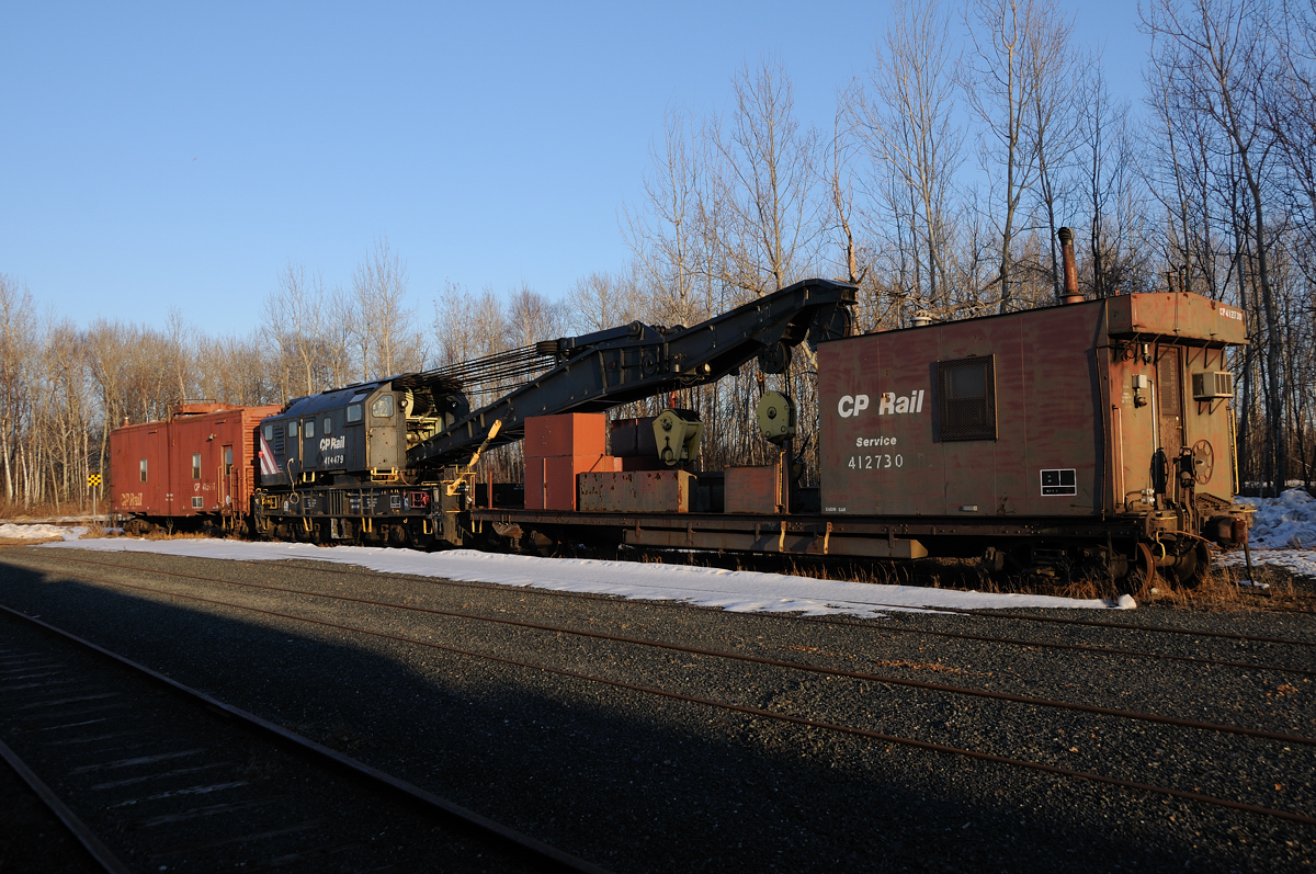 Inspired from an earlier post, I decided to dig through my collection to find this old 200 ton Crane (CP 414479) and Idler (CP 412730). At the time it had been sitting in Thunder Bay for sometime in the "mini-rips" (C-yard) where light repairs were done on cars before CP closed it and moved the operation to their main Thunder Bay shops in 2008. Up for sale by CP, little did I know at the time a local scrap yard had purchased it. Within a couple weeks of taking this photo a yard crew grabbed the old hook and took it to the winning bidder, Lakehead Scrap. 

On a sidenote, the tracks in the "mini-rips" in C-Yard appear they will be sent to scrap yard. Although for the past few years its been used only to store OCS equipment and bad order coal cars in October 2012 the junction switch which led to the small stub yard were locked and OOS (Out of Service).