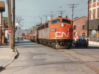 Even the locals are a bit awe-struck as CN's "Nanticoke" steel train rumbles up the middle of Ferguson Ave.N. in downtown Hamilton on its way up the hill thru Rymal, Caledonia, Hagersville and Garnet to the destination at the big steel facility on Lake Erie, about a 36 mile trip.
Power this day is CN 9169, 9196, 9172 with a rather short train. Caboose at each end so power can run around train upon return.