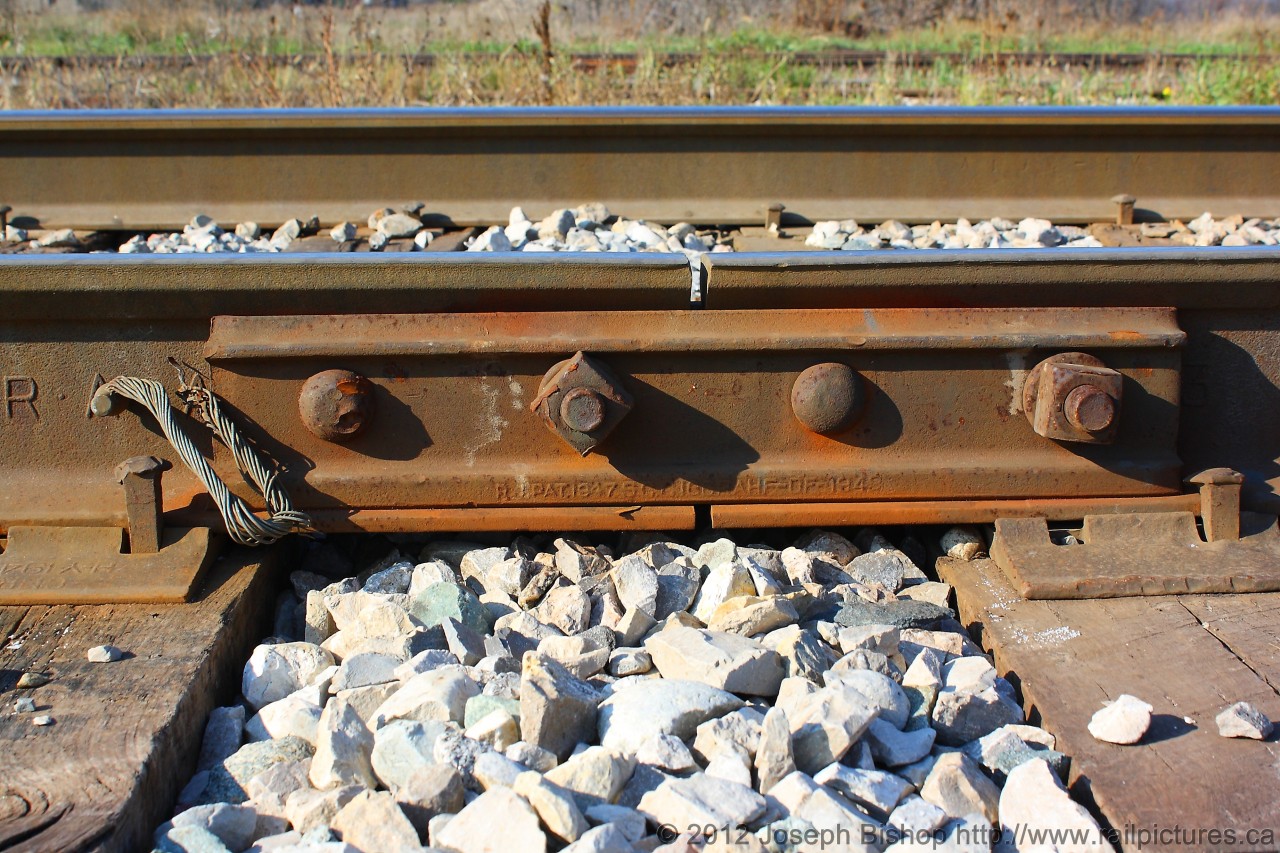 Pictured is a joint bar on the CN Hagersville Subdivision.  Every day the SOR runs two trains across this track.  Their main commodity is fuel from the ESSO plant in Nanticoke and steel from the US Steel works also in Nanticoke.  A joint bar holds together two pieces of track with four bolts in total.  What is cool about a joint bar in this shot is that all the bolts are not facing the same way.  This is done so that when a derailment occurs there is less of a chance of having the track seperate and made the derailment more severe.  The joint bar in the photo was manufactured in 1947 and has seen many changes to this line over the last 65 years and will probably be around to see many more years of change.