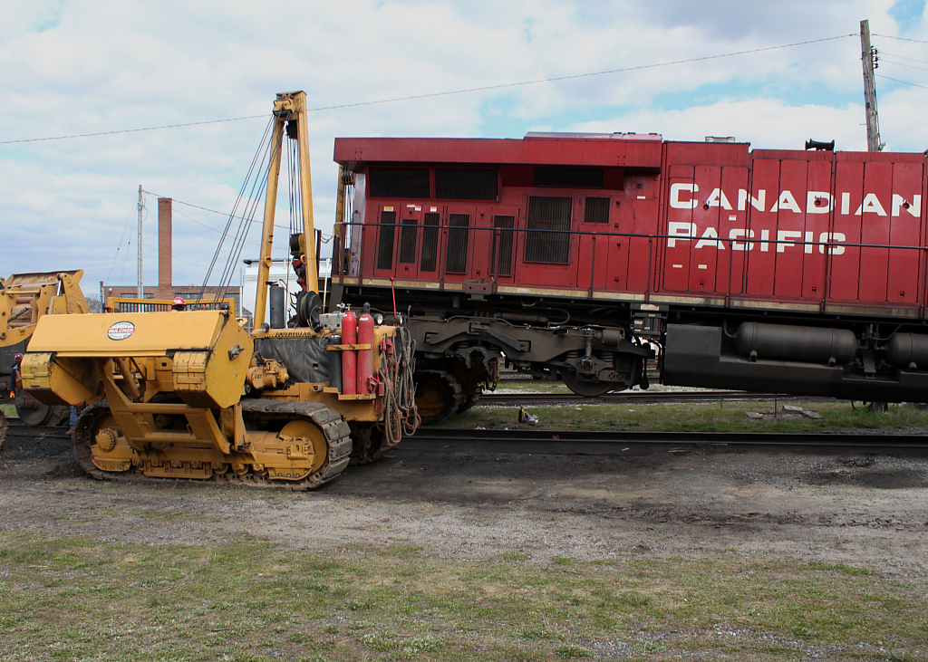 With the defective wheel set removed which can be partially seen to the left of the side winder, 8725 hangs in the air waiting for the dummy axle to be slid into place. Photo taken with permission by a CP Mechanical Services employee wearing all the required PPE.