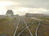 At the end of Hudson Bay Railway's Herchmer Subdivision lies Churchill, Manitoba. At left VIA's Hudson Bay sits at the station having wye'd before it's arrival with passengers on board. The passenger train will head south later in the evening. On the right is the recently arrived general mixed freight train from Thompson which has likely made several stops along the way. This train carried a 1919 vintage heavyweight combination coach/baggage until late 2000 painted in VIA colours. The true mixed train status was finally dropped with all passengers being accommodated on VIA #692 and #693. The headlight seen behind is GATX 2683 and its crew waiting to resume their duties of switching grain cars to be off-loaded at the nearby port destined for export to foreign markets. 