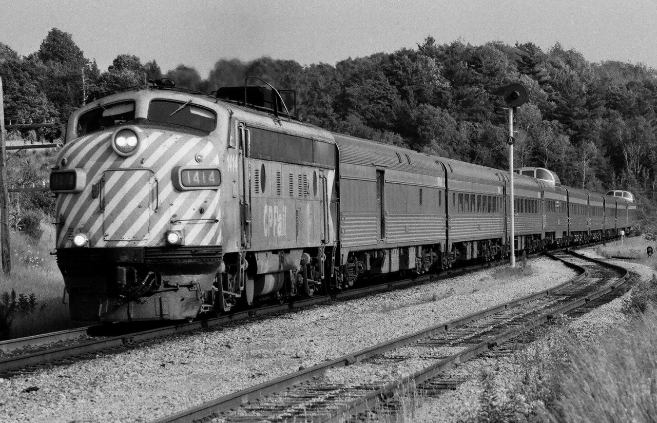 The Ted Ellis image showing a single CP Rail   F unit on the Soo-Sudbury CP Rail freight prompted me to dig up this Kodak Plus X negative: One unit nine cars. CP Rail train #11 – the Toronto section of 'The Canadian' – works through Palgrave, Ontario. The engineman must have the throttle of CP 1414 placed in notch 8, that FP9-A could be heard for miles! 

>> How about a single unit contest? >>First generation only single units  (where are all those 8921 RSD-17 shots?) <<.

[What's interesting: So how did the CP Rail 'The Canadian' become an all season short train?

The summer season eight car ( the nine car train in this image is unusual) Toronto section of 'The Canadian ' was common in the 1970's but uncommon prior to that. Let me explain. A comparison of the CPR 1966 passenger train time table to the 1971 time table show a dramatic contraction. Stations served by CPR trains, shown in the company public timetable, contracted from 3 pages to one lone page. Very evident that CP Rail executives had given up on passenger service. 

I rode 'The Canadian' in August 1970, Toronto to Vancouver (three nights westbound) and return, boarding (entraining) 'The Canadian'  in Toronto, Vancouver, Banff, Calgary and Winnipeg. Five different consists. What really impressed me was the professionalism and care of the crew and on board staff – from the Sleeping Car Conductor, Train Conductor, Trainmen, Dining Room Car staff to the Porters. They all had incredible pride in CP Rail's flagship transcontinental train.  

And quite the train, the only train, given The Dominion's last summer was 1966, replaced by the one summer season Expo Limited (for the Expo 67 Montreal (international ) Exposition. For the 1970 Summer season (August 1970), west of Sudbury The Canadian is a minimum eighteen cars ( I'd like to see someone model this!) : nine sleeping cars (five Toronto (likely 3 Manor, 2 Chateau), four Montreal (likely 2 Manor, 1 Chateau, plus 1 Manor or Chateau),  two Dining Room Cars, two 100 series coaches, two 500 series Skyline (coach – coffee shop), two 3000 series Baggage-Dormitory and the Park Observation – Sleeping car (Montreal). ( no tourist sleepers :the fourteen section U series tourist sleepers (22 were re-conditioned for use on The Canadian) may have been retired about the same time the Dominion was discontinued (can some confirm?)). 

West of Sudbury, normal power is two CP Rail 1400 series FP7A or FP9A plus one 1900 F7B GMD built units, all geared for 89 miles per hour – the latter is important, west of Thunder Bay to Calgary  'The Canadian'  is western Canada's  'Rapido', a sharp contrast  to the eastern portion of the trip (i.e. east of Fort William (Thunder Bay). [1970 schedules: The CN Rapido, on double 90 m.p.h. track Montreal to Toronto 335 miles average speed with two scheduled stops: 67 mph and that may be not quite fair: so how about CN Tempo train 144 Windsor to Toronto  228 miles with six scheduled stops average speed 52.6 m.p.h. , whereas the CP Rail train #1, 'The Canadian', on single 75 m. p. h. track  Calgary to Moose Jaw  433 miles average speed with six scheduled stops: 53.4 mph]. 

Toronto section power would typically be one CP Rail  FP7A or FP9A , either a 1400 or 4000 series plus one MLW RS-10 road switcher. So a typical 1970 summer season Toronto section is five sleepers, one Dining Room Car,  one coach (plus one Toronto-Sudbury coach on long weekends), one Skyline, the Park (Toronto-Sudbury only) and one Baggage-Dormitory. Some trips included  an  Express car (Toronto – Sudbury only).  And presumably the 1966 to 1969 summer season consists  were similar.

Ok, so back to how The Canadian became the mini twelve car train – west of Sudbury - of the 1970's that we are all familiar with. Upon my return from 'The Canadian' adventures, late August 1970,  I was riding the Coxwell TTC streetcar to work and on my seat was the daily Globe and Mail folded to the page on an article about the CP hearings in Ottawa by the Canadian Transport Commission (the predecessor to Transport Canada). The CP's position on passengers is straightforward: we want out. The CP Rail  1970 proposal: daily summer service for the 'The Canadian'  and for the off season - the October to May eight month period - the  proposal is to operate 'The Canadian' three times per week.     H'mmm, wonder where....Remember, this is 1970. What was going against the CPR was that the CNR was still actively pushing passenger service, but the CN really did not have a choice being a ward of the federal government. For some reason the CTC Commissioners did not seem to be able to grasp the full difference between reporting to shareholders (CP Limited shares being a publicly traded) verses being a ward of the government (ie CN). (perhaps some viewers may have better recall on the details of the CP Rail CTC hearing/ proposal). 

In the end CP Rail  was compelled by the CTC to continue operating 'The Canadian' daily all year round - after all the CNR was not asking to reduce its transcon service to tri-weekly - irregardless of the strong evidence that transcontinental train travel had become (and remains today) a summer tourist operation. The CTC did allow CP Rail  to 'rationalized' the service - to limit costs hence limiting revenues during peak travel periods – a death knell for the service.  Hence commencing 1971 CP Rail limited the size of the rationalized 'The Canadian' to twelve cars west of Sudbury. (presumably in part that limit was set do to what two F's could handle). 

One can only wonder what would have transpired if CP Rail was allowed to match the service to demand. Certainly the experience of the Southern Railroad (The Southern Crescent) comes to mind – that company declined to join Amtrak. Perhaps CP may have declined to join Via? We may never know. The view here is some service is better than none at all  - and what do we have today on the CPR route? NO SERVICE. And it appears we (the public) are now stuck with the CN route (& four nights) on a SUMMER tri-weekly basis, and further off season reduction in services forthcoming for 2012-13. 

Not knowing at the time, but it appears that my August 1970 rides on The Canadian were the final month of  an eighteen car CP Rail “The Canadian” ! ]

And for all those modelers out there: here is proof only one CP Rail F unit is needed for "The Canadian" !

Summer 1978 negative by S.Danko.