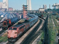 The TTR, the way it was - at Bathurst Street. From the extreme right in the CN Spadina Coach yard the Turbo train, Tempo equipment, in far distance a Via CN FPA-4, the CN Spadina Shop coaling tower (and behind it is the Spadina Ave. overpass and the smoke stacks of the steam heating plant), a CN GP-40 is framed by the coaling tower, a MLW S-13 (CN 85xx ) pushes conventional equipment through the car wash, CP Rail Train #11 'The Canadian' with CP Rail FP7-A #1404 and a F7B #19xx with extra coaches (is on Toronto Terminals Railway track), the never used TTR control tower, another MLW S-13 (CN 8519) shuffling freight cars, the lower Front Street freight yard with surplus stored single level GO Transit equipment. Note the TTR switches are manually operated – the front of the TTR Switchtender's shack is in the extreme lower right corner.  (anyone modeling this location ? )  The time: 17:20 on  an early September 1978 afternoon. Kodachrome by S.Danko
