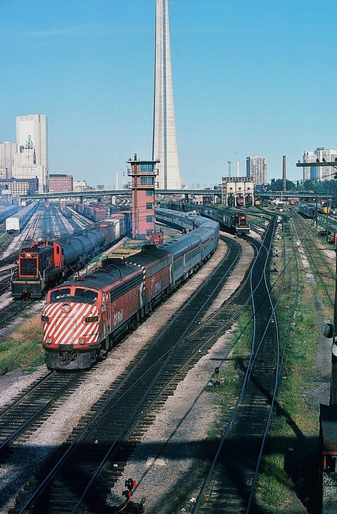 The TTR, the way it was - at Bathurst Street. From the extreme right in the CN Spadina Coach yard the Turbo train, Tempo equipment, in far distance a Via CN FPA-4, the CN Spadina Shop coaling tower (and behind it is the Spadina Ave. overpass and the smoke stacks of the steam heating plant), a CN GP-40 is framed by the coaling tower, a MLW S-13 (CN 85xx ) pushes conventional equipment through the car wash, CP Rail Train #11 'The Canadian' with CP Rail FP7-A #1404 and a F7B #19xx with extra coaches (is on Toronto Terminals Railway track), the never used TTR control tower, another MLW S-13 (CN 8519) shuffling freight cars, the lower Front Street freight yard with surplus stored single level GO Transit equipment. Note the TTR switches are manually operated – the front of the TTR Switchtender's shack is in the extreme lower right corner.  (anyone modeling this location ? )  The time: 17:20 on  an early September 1978 afternoon. Kodachrome by S.Danko