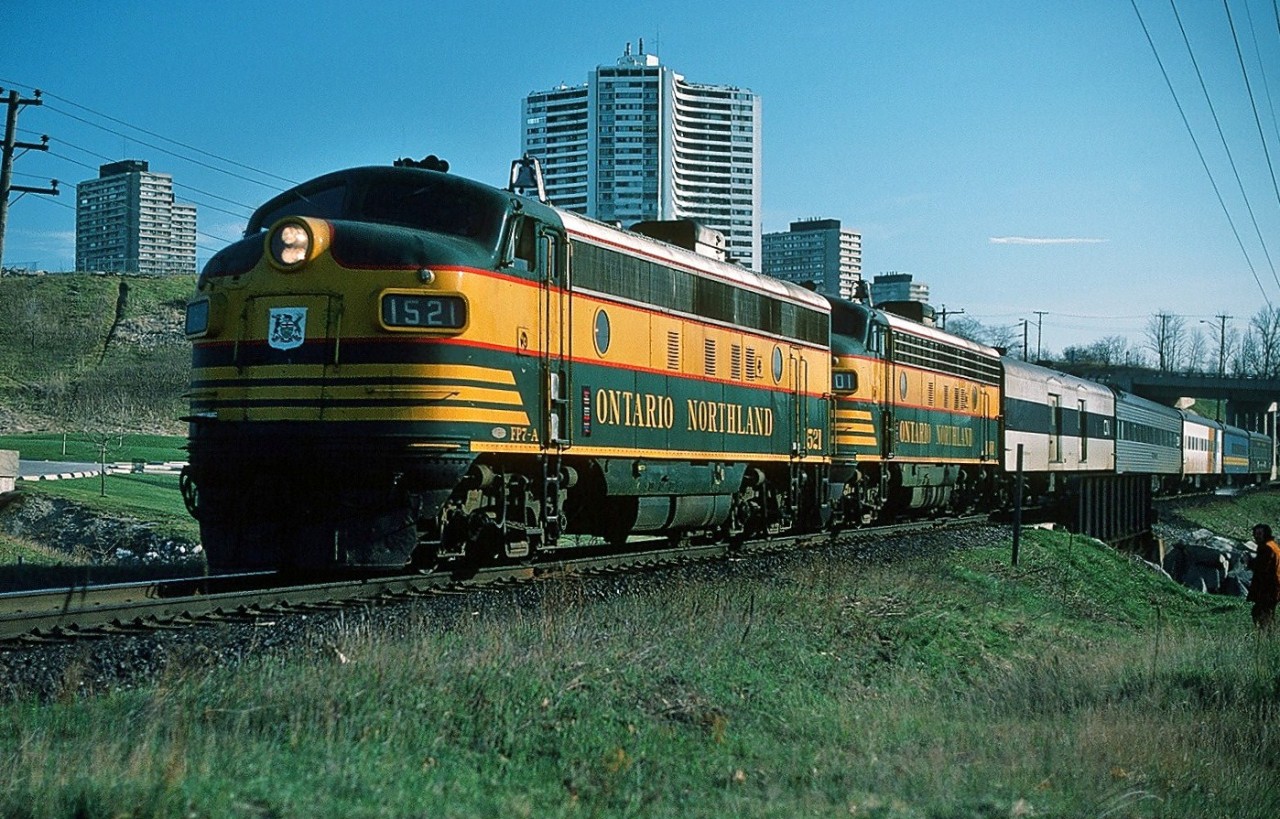 It's the Northland! Southbound at 07:45 (a.m.), after 545 miles with only 6 miles to Toronto Union Depot, the towers of Thorncliffe Park provide a backdrop for Via CN train #98 powered by ONR's classic green and yellow FP7-A #1521 and #1501. The power is coupled in the normal Northland 'elephant style'. The last passenger pool train in Canada? April 1977 Kodachrome by S.Danko.