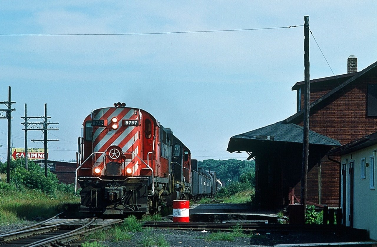 At 15:55 on August 26, 1984 witness CP Rail extra #8737 at Blind River, Ontario. 
Being not familiar with this territory, can someone confirm the direction of travel? Status of the station? 

Somewhat surprised by this find (and given that it was expected most movements would be at night)hence unable to record that second leased unit nor the third. 
I believe the Budd car was discontinued about 6 years prior (?). 
( Irritation: Has anyone noticed that once the passenger subsidy ends (train discontinued) that the track deteriorates, and in some situations eventually the freight carrier shows up cap in hand for public (yours and mine) money to fix the freight tracks to allow continued freight service sans passenger service?). 
Kodachrome by S.Danko.