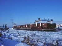 Heavy ice on the Detroit River prevents the tug F.A. Johnson, with the loaded car float Windsor, from docking at the CP boat slip in Windsor. Maneuvering above the slip, the Johnson hopes to wash the ice out of the slip so they can make the dock. With the help of propeller wash from fleetmate R.G. Cassidy (barely seen above the rail cars on the barge) the two tugs finally make landfall possible.

CP would then pull the barge and reload with cars destined for the N&W on the Detroit side of the river just above the bridge. The N&W also had slips at the CN boat yard about a half mile above this location. 