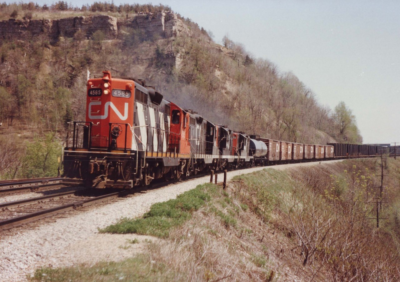 CN 4585, 4516, 4563, 4560, a quartet of GP9s, powers a westward train up the long grade to Copetown under the watchful Dundas Peak on a beautiful spring day 35 years ago.