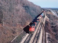 CN 5561, 5044 and 5570 seen westbound passing Mile 4 Dundas Sub on a crisp fall morning.It is a struggle all the way to the crest of the grade at Copetown, around mile 10 or so, and this train is already struggling at about 20 MPH or so.
In the background is Sydenham Rd bridge, the siding, long removed, is for the old Canada Crushed Stone plant that was at the top of the hill out of sight on the left. On the extreme right one can see a scale house and some trackage, I believe was in control of Steetly Ltd., at the time, stone operations, and now the land is part of a housing survey and little evidence of the past exists.