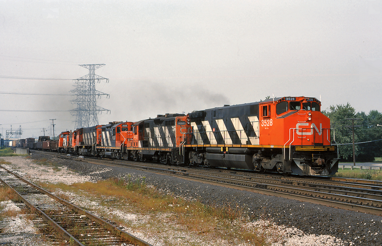 CN 3528, 4417, 4100, 3527 and a pair of SW1200RS' lead an eastbound freight through the plant at Burlington West.