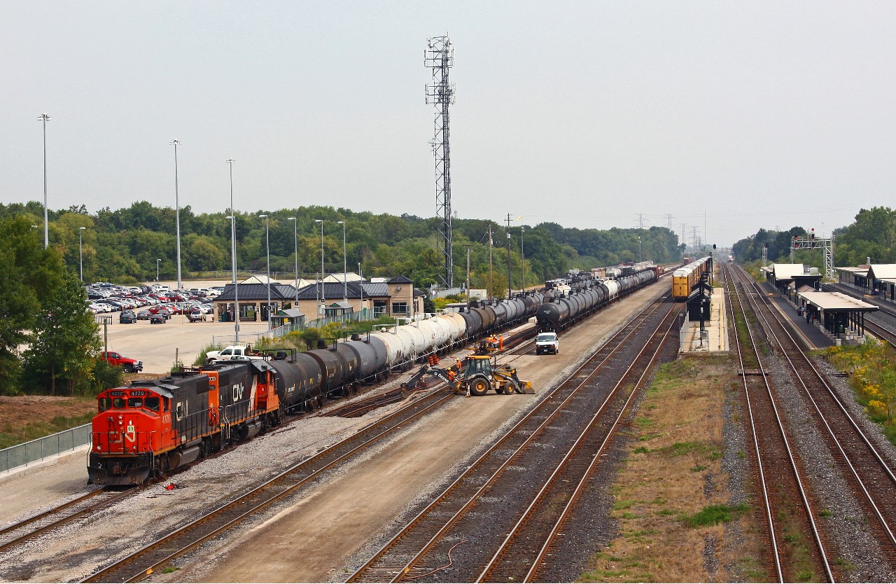 CN 551 backs a cut of tank cars from Petro Canada into the lower part of Aldershot yard as a foreman and track gang work on straightening out the new yard track added over the summer.