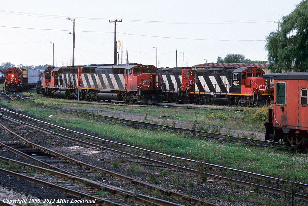 In better times, power for road, local, and yard jobs lays over at the engine terminal at Niagara Falls. Visible are CN CN 5453-5116-1391, 4123-4138, 7276-234. All are at rest except 7276 and 234 seen drilling the yard on the extreme left. The maintrack, the weeds, and the willow are all that remain. 1700hrs.