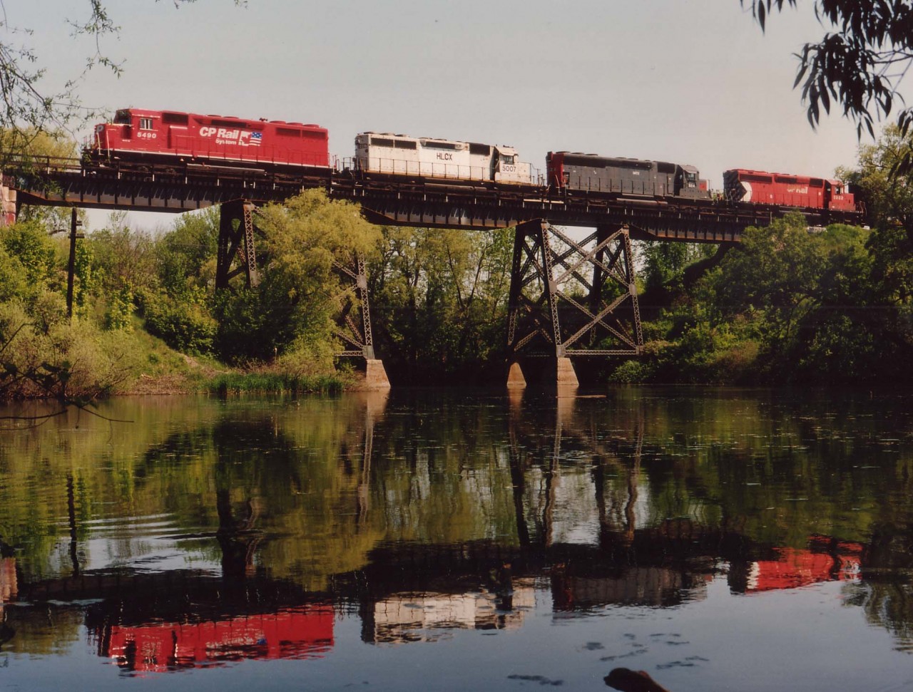 While I was wandering at Campbellville this westward train came at me out of the early morning sun. So hopped in the car, booted it down the 401  to Woodstock and as far west as the bridge over the Middle Thames River in Thamesford before I thought I had a great place for a shot of this colourful power. Having come this far, it was nothing to wade into the muck pond and get the feet wet.  CP 5490 (SD40M-2), HLCX 5007, HATX 924 and CP 5983 was the power. And that was all that would fit on this tight bridge shot. Beautiful warm morning; the kind of day being trackside is all about.