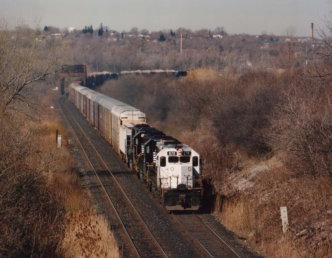 This is a follow-up to Mike Lockwoods image (i.d. 7437)from that era of great variety on CP Rail. Leading NS autoparts train #328 is CP 672, a KCS castoff later seen as CP 5417 over the system. Unfortunately this unit never wore a "CP" on the nose as 672, but just 'CP Rail" in red on the flanks. Behind the 672 are NS 3273 and 6673. View of this eastbound is at CN Iron Br., around the curve out of sight is the bridge over Welland Canal.