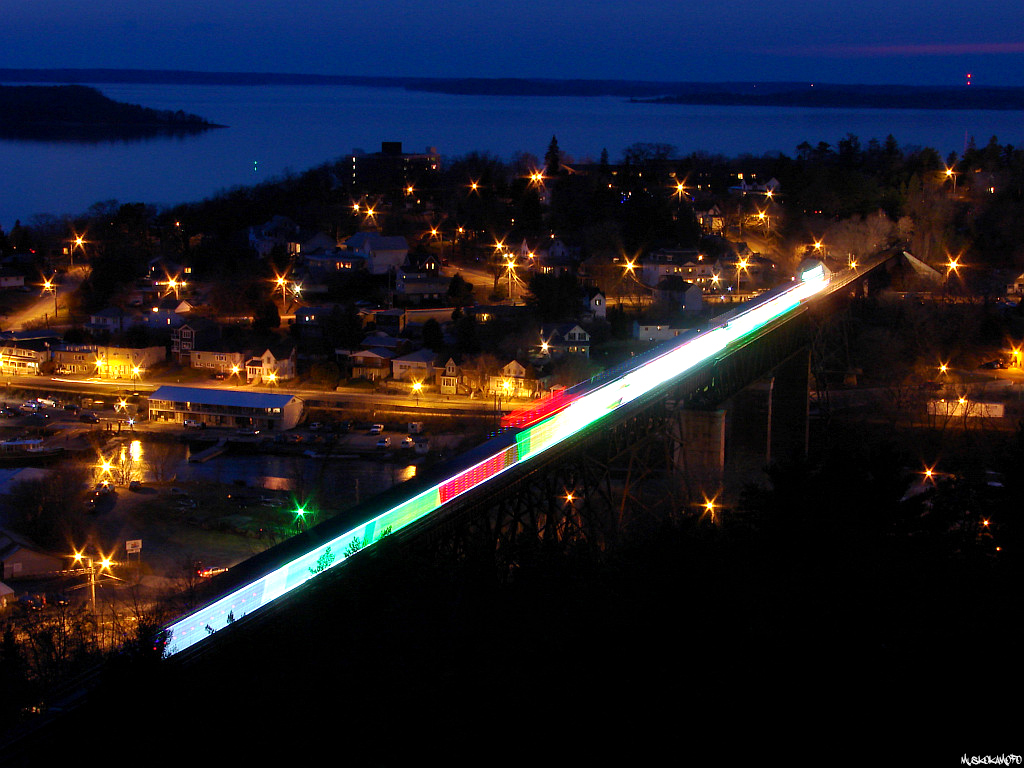 CP 9815 North with the Canadian Holiday Train comes to a stop on the trestle in Parry Sound for a quick photo op, splashing some color into a dull scene without any snow. Before long they'll be back on the move a few hundred feet to pull up to the old CP station around the corner to accept a few donations and play a few songs before carrying on towards Sudbury, and the rest of Canada. I was surprised in 2009 I was the only one to brave the cold climb up the old fire tower and go for this angle!