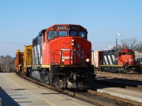 CN 9437 leads a loaded rail train past "AR Illinois" 4138 parked in the yard.