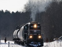 <i>Barrie-Collingwood Railway chase 1 of 7.</i> In February 2009 I set out on a mission to capture the infrequent train to Collingwood, Ontario. Arriving at the BCRY shops around sunrise I talked with some employees to confirm the train would be running to Collingwood. Sometime after 08:00 the crew brought the engine out the stall and began their minor switching duties grabbing three cars destined for Canadian Mist distillers at the end of track in Collingwood. After waiting for a northbound CP the crew was given the light and proceeded westbound. A few employees followed the train westbound, protecting the grade crossings and chipping out any build up of ice in the flanges of the crossings. In this scene those employees watch as the engineer throttles up the old GP9 as their westbound train crosses the Sunnidale Tosorontio Townline along County Rd 10, just west of Angus, Ontario. 