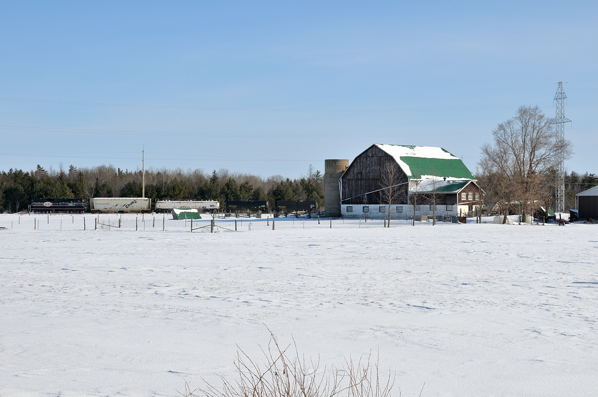 Barrie Collingwood Railway chase 2 of 7. Just west of New Lowell the westbound train passes through the rural farm fields of Simcoe County with their train of three cars for Canadian Mist distillers.