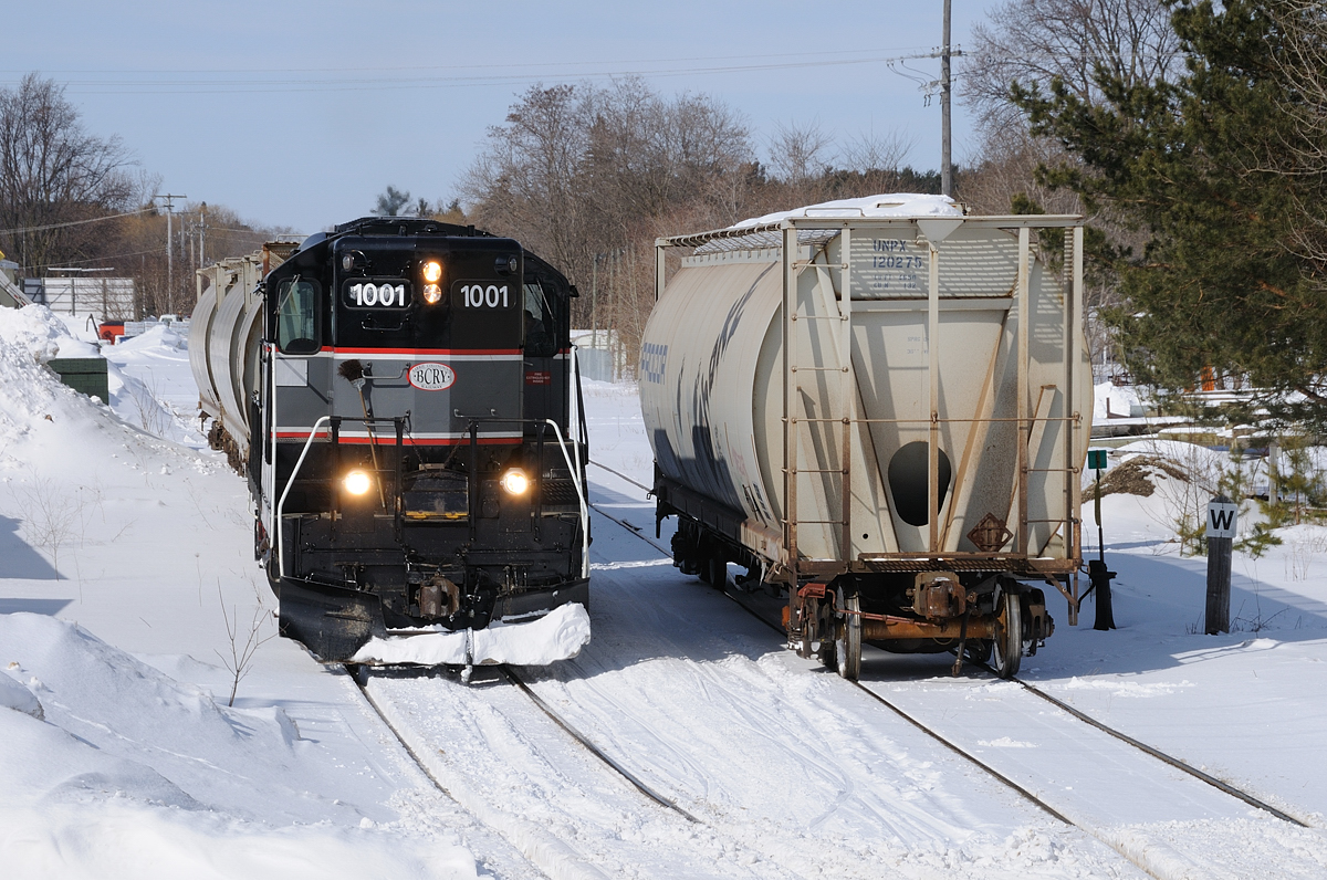 Barrie Collingwood Railway chase 6 of 7.After a bite to eat at Canadian Mist, the crew have began their return to trip to Utopia. They had a stop at F.S. Partners in downtown Stayner to pull 3 empties and spot 1 load. The crew would leave their one load on the "main" as they 'nosed' into grab the three empties. The crew grabbed the one load on the main and spotted it. One things that I found really interesting of this branchline (/spur) were the old wooden whistle posts. Most sported the metal sign on them although they all originally had a 'W' engraved in the wood. Good ol' classic branchline characteristics that will disappear with the abandonment of this light rail line.