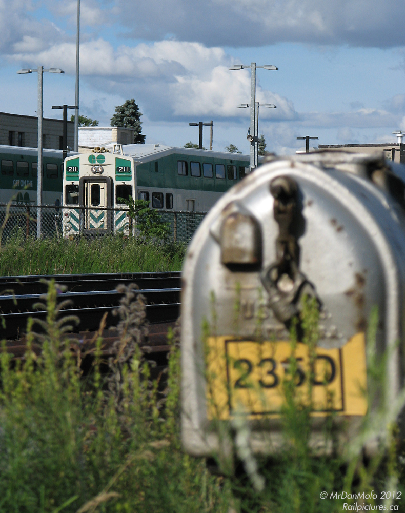 Lumbering into the station at the end of the line with a load of Georgetownians, GO 216 leads train #207 into the Georgetown communter compound to unload. In the weed-grown foreground, old signal 235D sits, guarding the west end of the Georgetown "station track", long disused and disconnected. It along with the remaining track would be removed a year later, only to be later reinstalled (!) for the planned GO Georgetown line expansion to Kitchener.