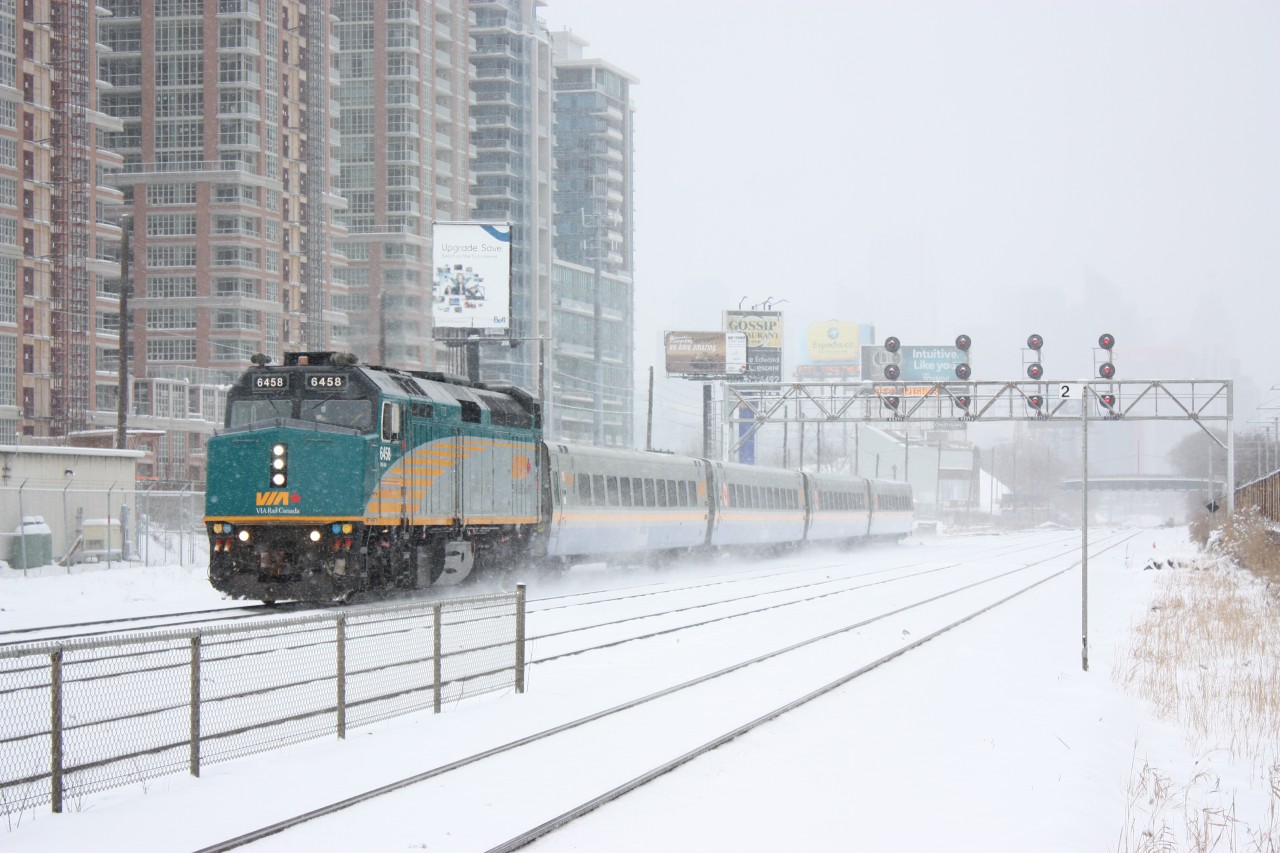 VIA train #73 races through Exhibition station past one of the rare surviving search light signal bridges left on the Oakville sub. Most have been replaced with new three colour hooded signals.