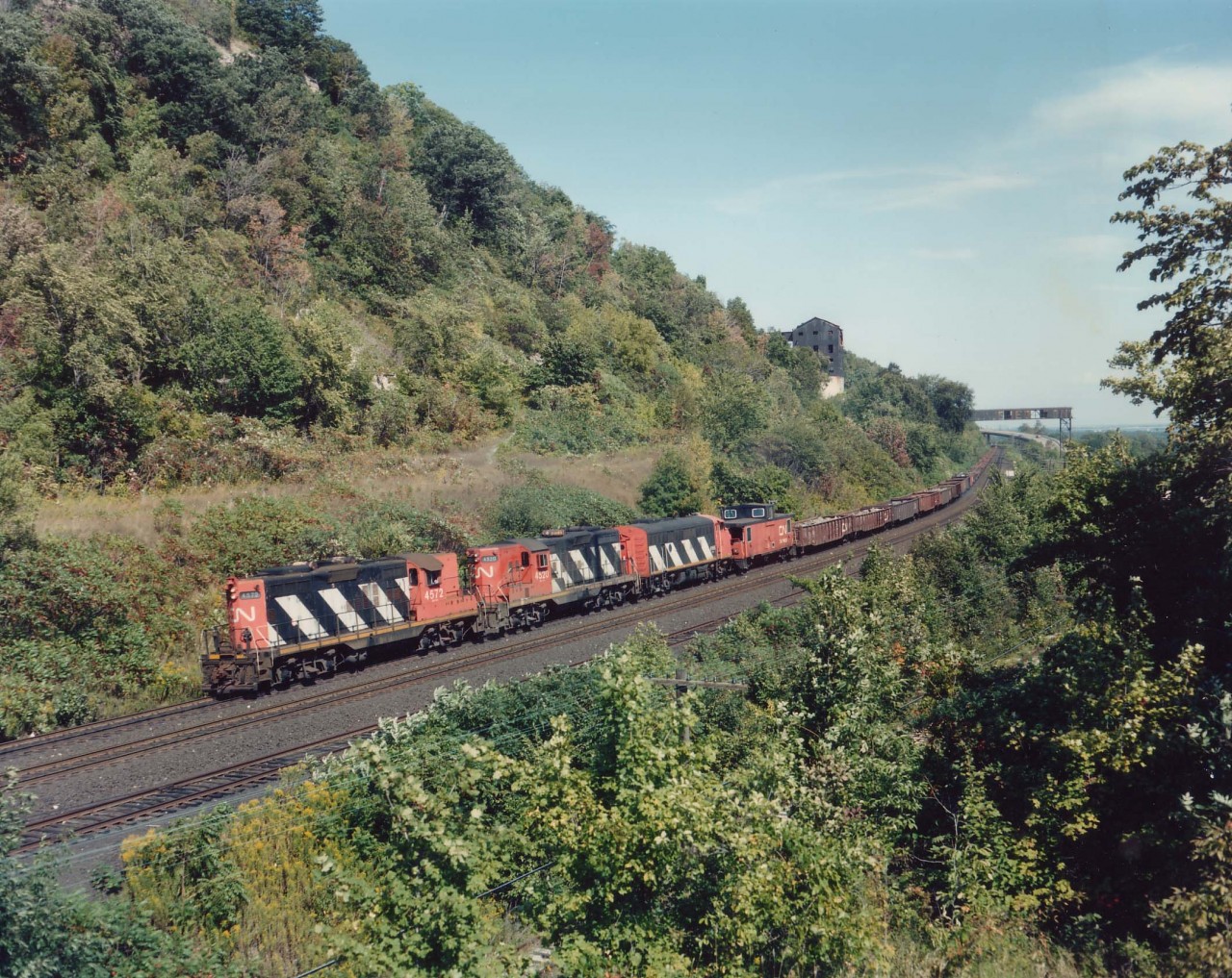This view, from a hillside location now obliterated by ever expanding foliage, shows #725, "The Nanticoke" with CN4572, 4520 and 9166 the power heading West to Brantford and then south to Waterford & Nanticoke. The view was imaged with a 4x5 Speed Graphic using Kodak Vericolour III type S sheet film for anyone interested.
For Mr. H.T.Greb  :o) in the far distance one can see the old conveyer structure that RP.ca #7210 was imaged from; the south end long removed and screened off. Holes in the structure made for good viewpoints, holes in the floor a must to avoid.
It is only grasses where the track used to run up to the large building where cars were loaded when the operation was in full swing, and just barely in the weed above the cab of the middle unit one can see where the old incline ran up the hillside. It is now a hiking path. Building and overhang removed in the mid-90s, I think.
