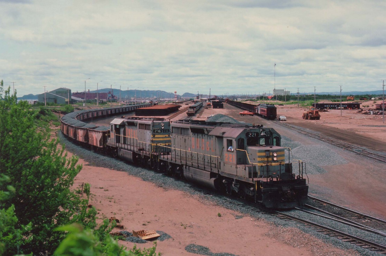 Iron Ore hauling Quebec North Shore & Labrador locomotives 221 and 236 are seen near the Sept Iles yard entrance with a loaded train from the North.
The 221 and the 236 were rebuilt in 1995 and are on the roster as SD40-3 #319 and #321.