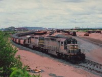 Iron Ore hauling Quebec North Shore & Labrador locomotives 221 and 236 are seen near the Sept Iles yard entrance with a loaded train from the North.The 221 and the 236 were rebuilt in 1995 and are on the roster as SD40-3 #319 and #321.