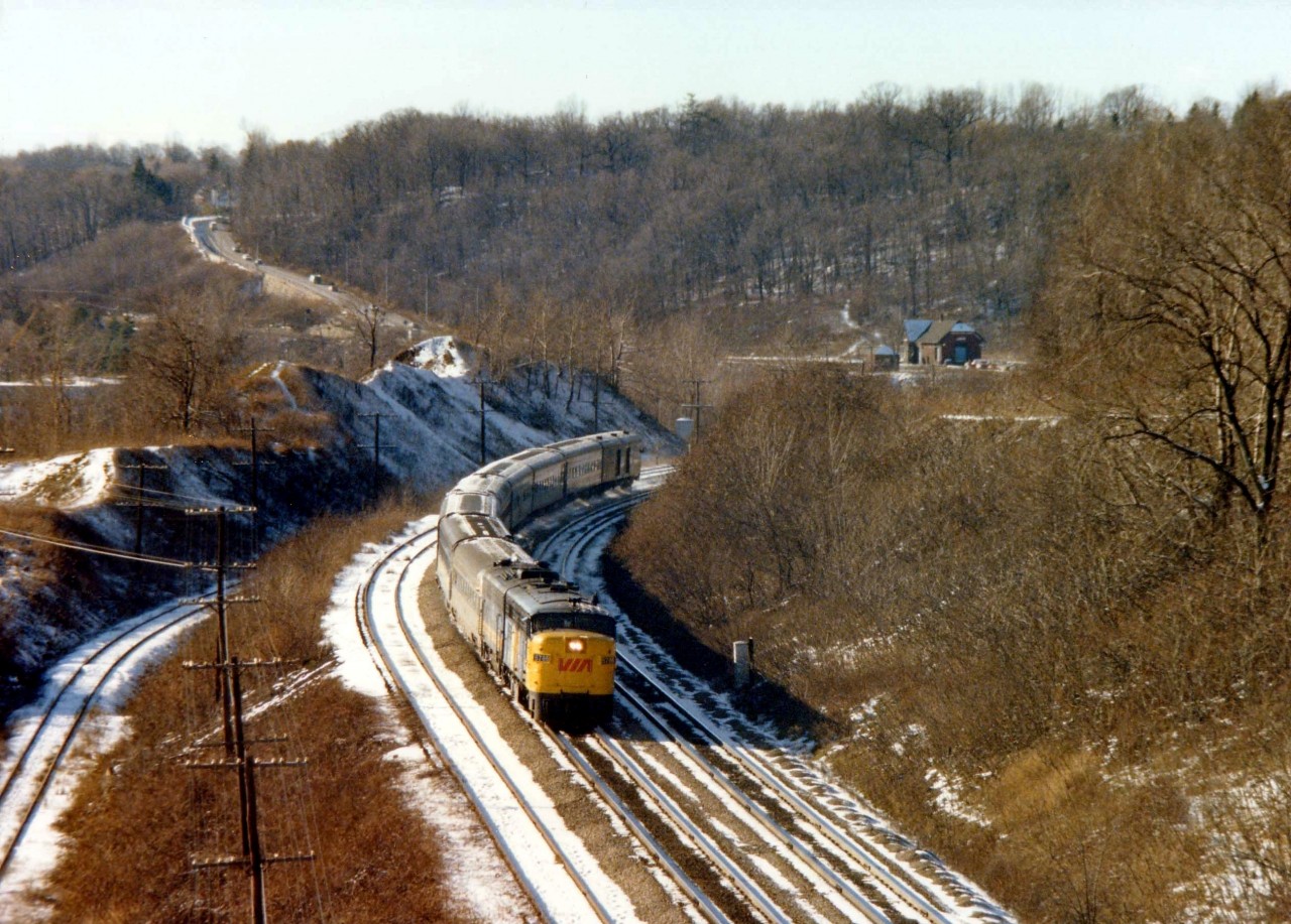 This is my favourite image taken at Dundas. A very unusual angle; looking west toward the old Dundas Station (demo'd in 1986)and the MoW shanty, as well as a few automobiles to prove the location was not yet totally devoid of customers.
Track on left siding for stone cars from CCSL (now shut down) and possibly Steetly, which operated at this time a small crushed stone and gravel business. Off to the far left is the Steetly connection, lifted in the mid 1980s.
Lead unit on #72 is VIA 6786. Location from where this image was taken, the CCSL conveyer overhang, was dismantled in 1989, according to my notes.
