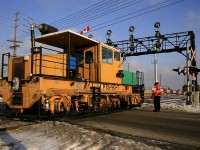 A Plasser Dynamic Track Stabilizer, part of a long parade of maintenance equipment departing Oakville Yard this day, crosses over Chartwell Road heading west.