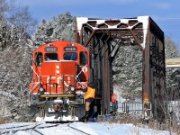 After dropping 6 cylindrical hoppers at the KWH Pipe plant at the north end of Huntsville Yard 4132 backs up to get back on the main so they can head back into the yard to finish up the switching they've been doing there all morning. The bridge in the background carries the CN Newmarket Sub over the Muskoka River northward to North Bay.