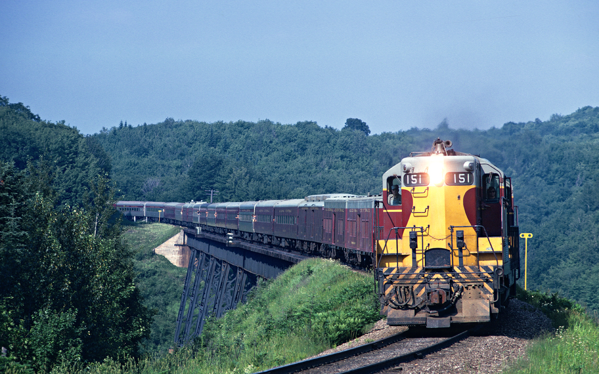 Southbound Train No. 2 is crossing the Bellevue Trestle on a nice warm summer afternoon. The Agawa Canyon Tour was becoming very popular then and as a result No. 2 kept getting bigger and later with all of the Flag Stops to deal with, as well as regular station stops. Within a couple of years the Agawa Canyon Tour trains would run as separate trains (No. 3 and 4) to Canyon and return as a second class passenger train.