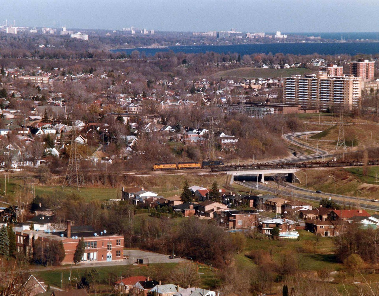 The TH&B version of the Nanticoke Steel Train was just into its' third week when this photo was taken. B&O 4801, C&O 3885 and 4828 are seen crossing the highway 403 after exiting Aberdeen Yard in Hamilton. The train will travel westward thru Summit and Jerseyville before turning south at Brantford. Nowaday this line has been reduced to a hiking trail, track pulled many years ago after a washout in Brantford deemed too costly to repair. The background of this photo shows Hamilton Harbour and Aldershot in the distance.